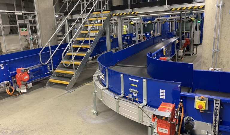 Powered curves for airport baggage handling